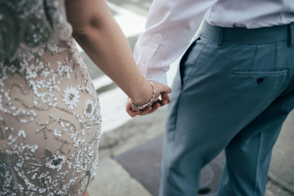 close up of bride and groom holding hands while crossing the street
