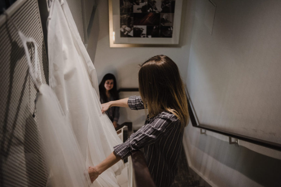 bride looking at her wedding dress hanging in the stairwell of the hotel room in Toronto