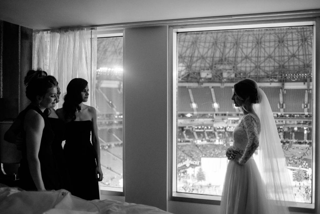the bride and bridesmaids are having a moment when they see the bride for the first time in her two piece Sash and Bustle wedding dress from Toronto