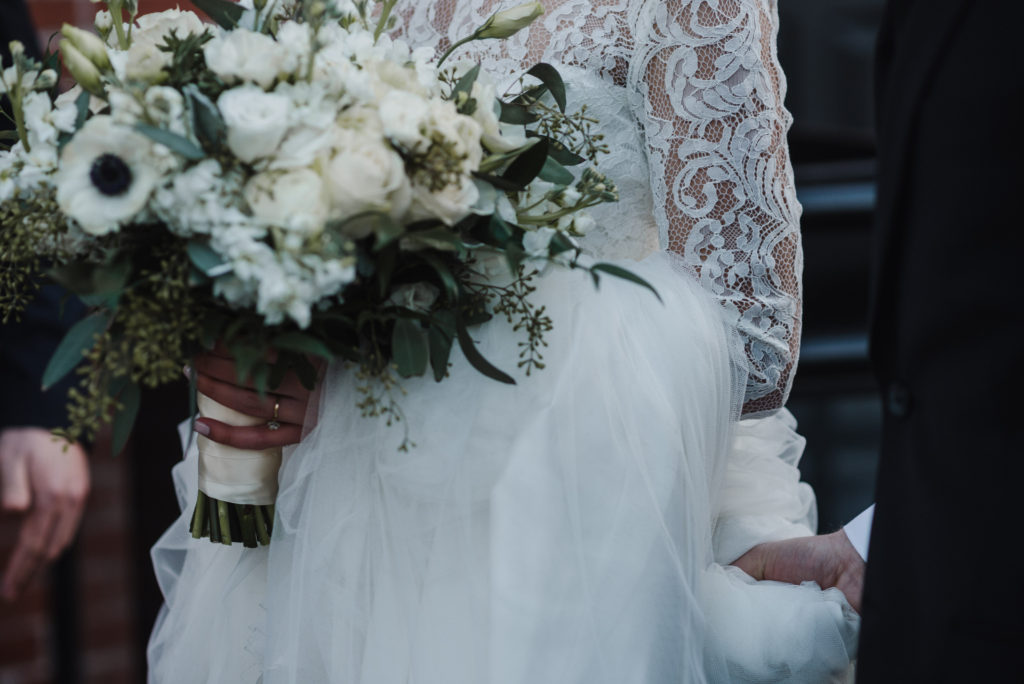 close up of the bride holding her bouquet and the lace detail of her dress