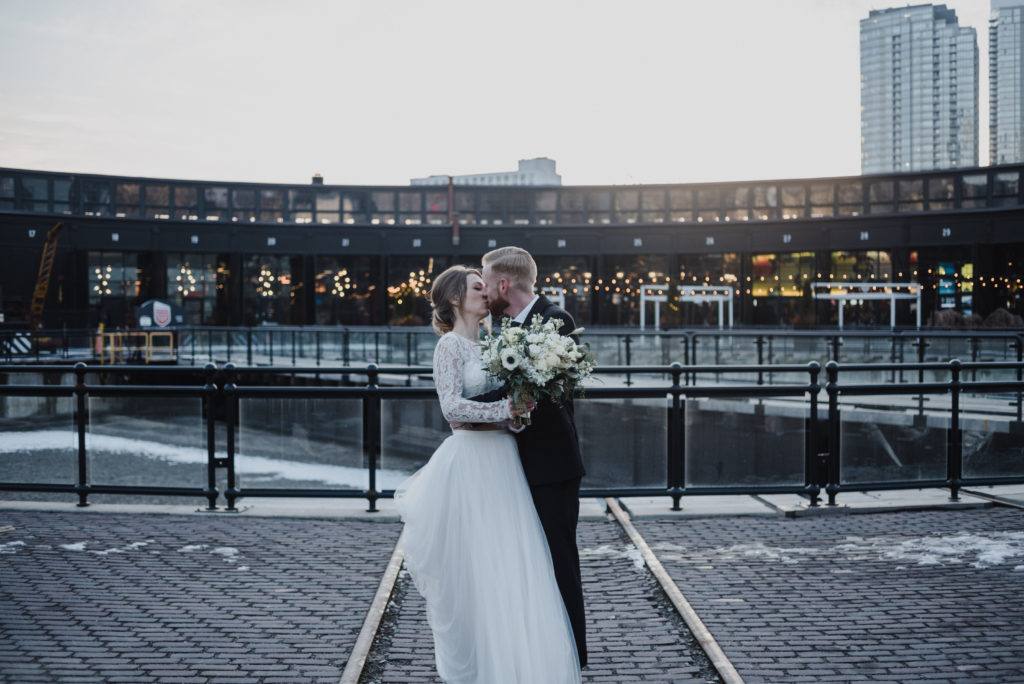 bride and groom kissing outside of steam whistle brewery in Toronto