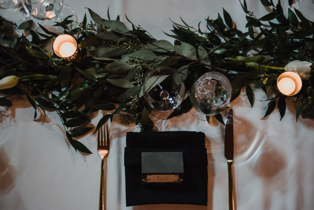detail shot of place setting with beautiful greenery and candles