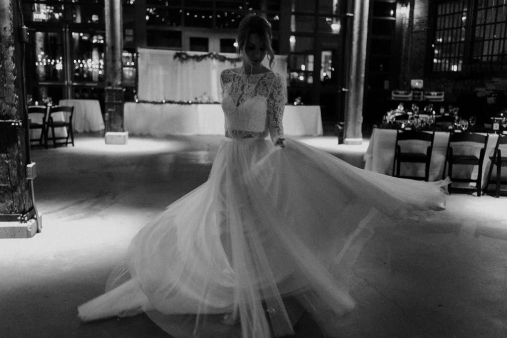 black and white photo of bride twirling in her dress in steam whistle brewery