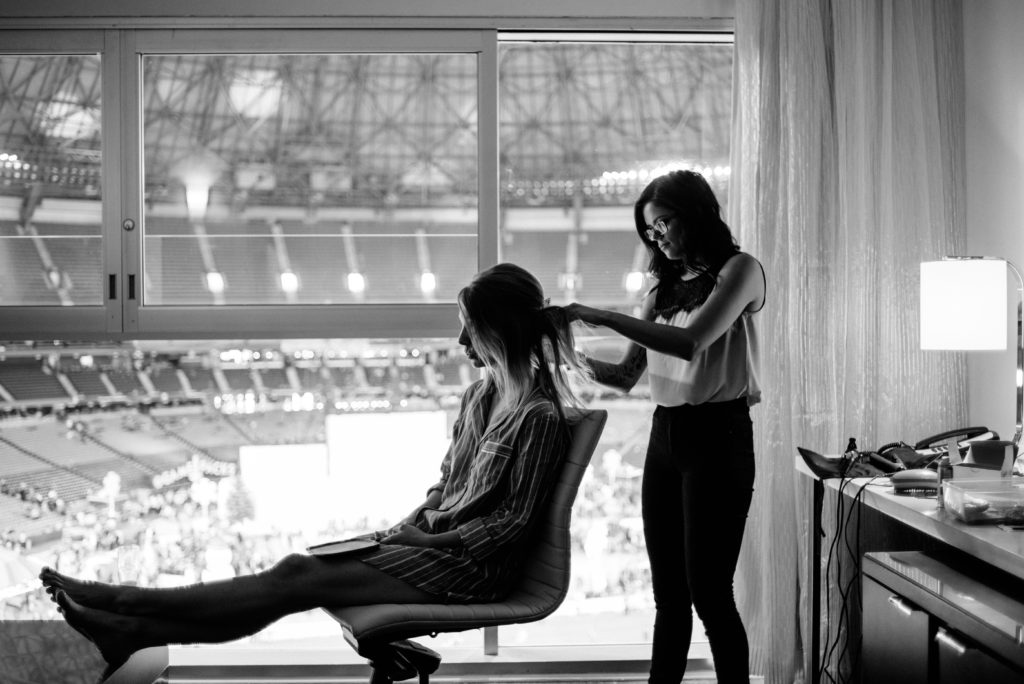 bride sitting on chair with hair dresser starting to get hair done for Toronto wedding