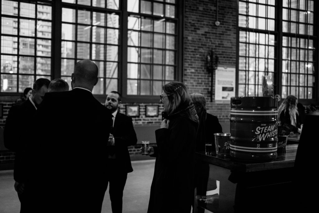 groomsmen greeting guests in the lobby at steam whistle brewery in toronto before the ceremony starts