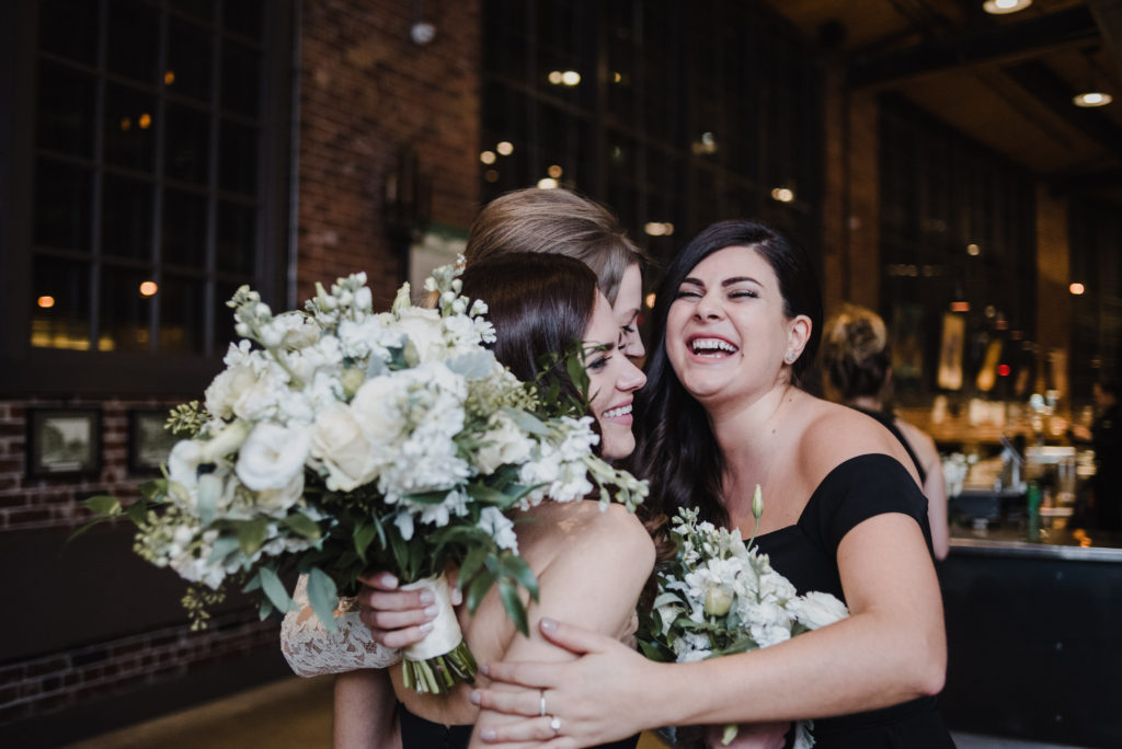 bride and her bridesmaids hugging after the ceremony at Steam Whistle Brewery 